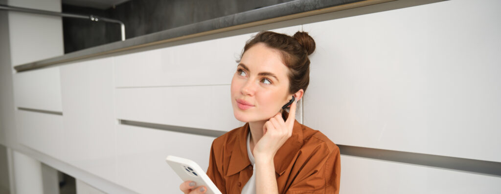 MCAS und ME/CFS - Literaturübersicht zu meinem Podcast bei Fasynation 5 Portrait of cute young woman in wireless headphones, listening music, watching video on smartphone and using earphones, sitting on kitchen floor